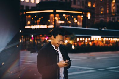 Full length of man standing on illuminated street at night