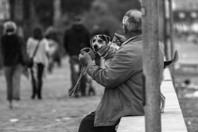 Man with dog while sitting on retaining wall