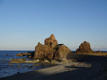 Rock formations on shore against clear blue sky