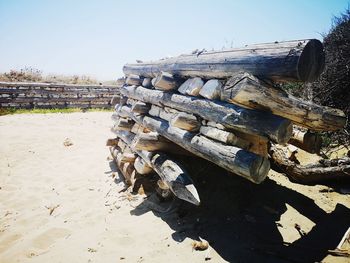 Stack of logs on field against clear sky