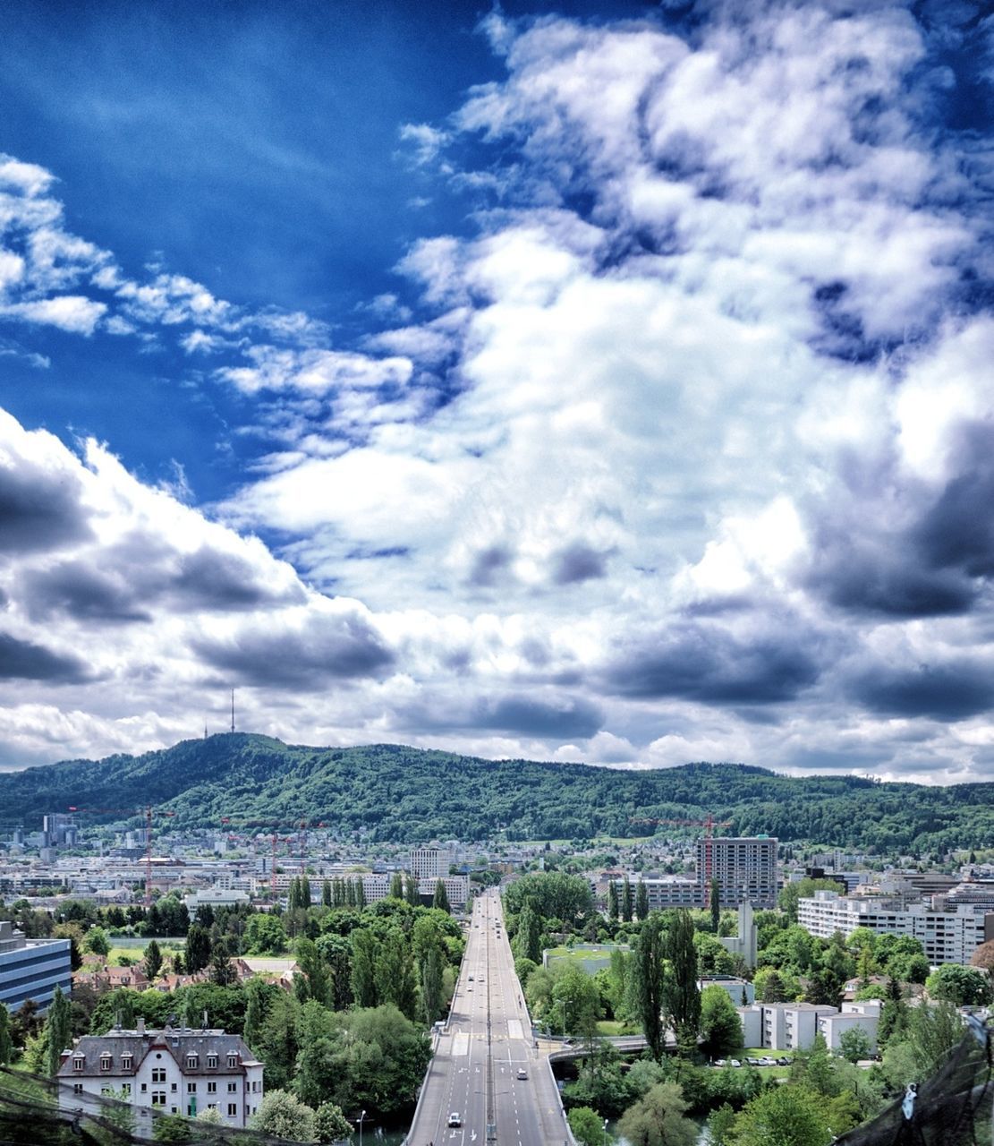 sky, architecture, cloud - sky, built structure, building exterior, the way forward, cloudy, cloud, mountain, transportation, road, tree, diminishing perspective, vanishing point, city, town, mountain range, high angle view, day, outdoors