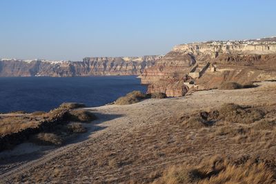 Rock formations by sea against clear sky