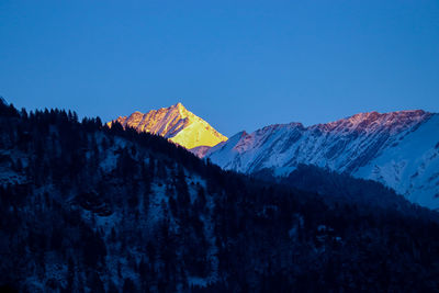 Scenic view of snowcapped mountains against clear blue sky