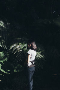 Portrait of woman standing against trees at night