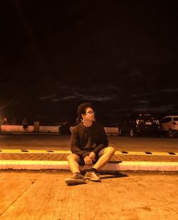 Full length of young woman sitting in car at night
