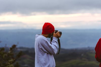 Man with red umbrella standing on land against sky
