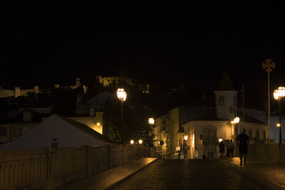 Illuminated town against sky at night