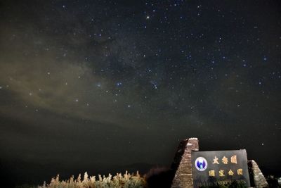 Low angle view of information sign against sky at night