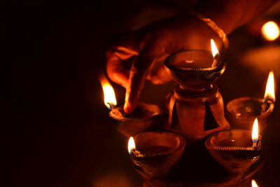 Cropped hand of woman adjusting tea light in dark at night