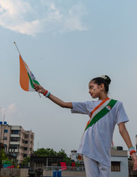 Cute indian girl kid holding indian flag against sky celebrating indian independence day 
