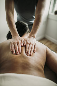 Detail of a massage therapists hands on the back of her patient.