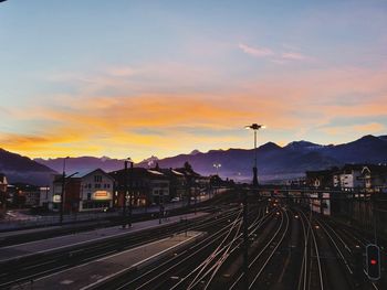 Railroad tracks in city against sky during sunset