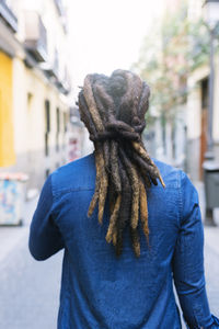 Rear view of man with dreadlocks standing on street