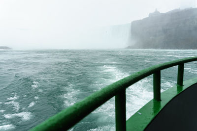 Close-up of railing by sea against clear sky