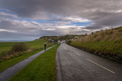 Road amidst field against sky