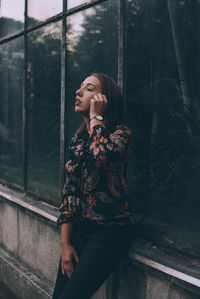 Woman looking away while standing on window