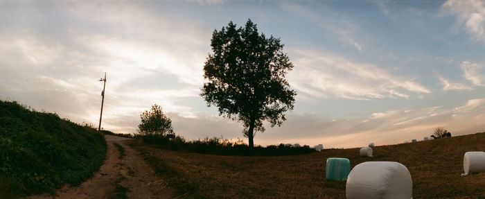 Road passing through field against cloudy sky