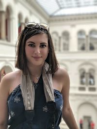 Portrait of young woman standing against building