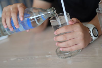 Close-up of hand pouring water in glass on table