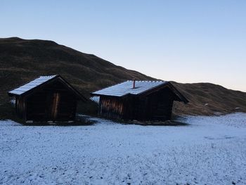 House on snowcapped mountain against clear sky