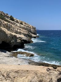 Scenic view of rocky beach against clear blue sky