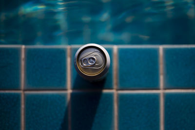 Selective focus, one can of white beer placed on the edge of the pool bright blue wate