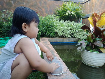 Girl looking at potted plants in yard