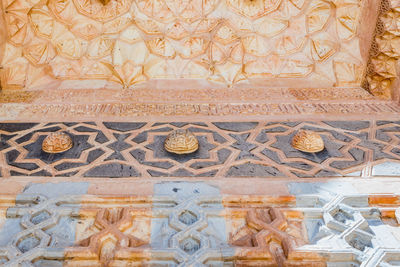 Close-up of carvings on tiled floor against wall in building