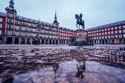 Statue in city against cloudy sky