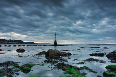 Lighthouse by sea against sky