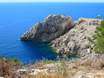 Rock formations by sea against blue sky