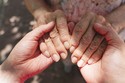 Woman holding hands of grandmother in sunlight