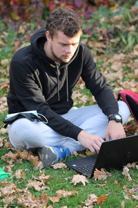 Young man sitting on field during autumn