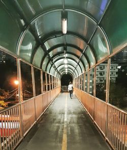 Rear view of woman walking on pedestrian walkway at night