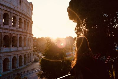 Rear view of woman in city at sunset