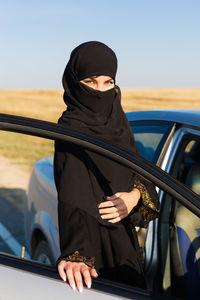 Midsection of woman sitting in car against sky