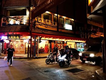 People walking on illuminated street at night