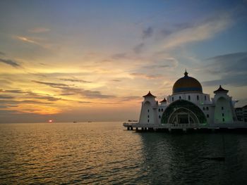 View of sea and building against sky during sunset