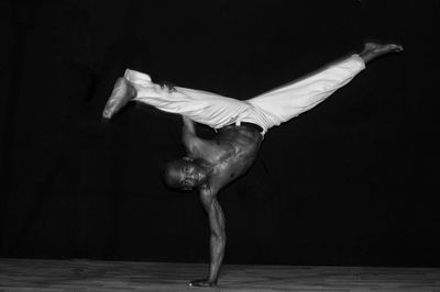 Midsection of man dancing against black background