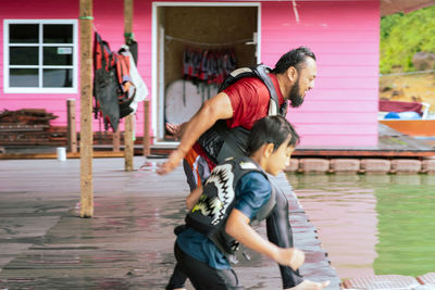 Young wet asian family wearing life jackets getting ready to jump into the lake.