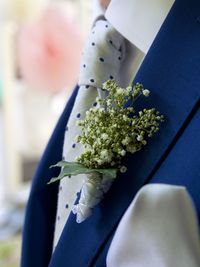 Cropped image of groom wearing suit with boutonniere during wedding