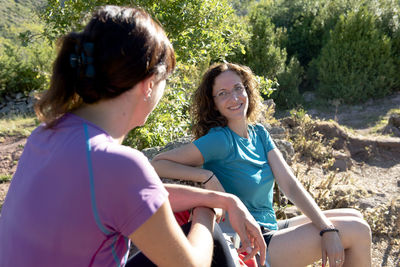 Two hiker girls resting and chating on a mountain path side.