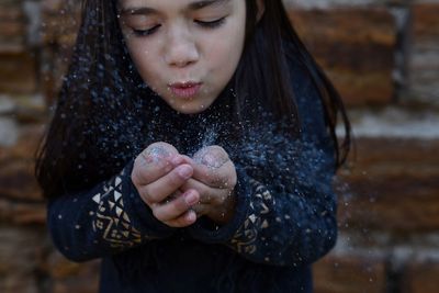 Playful girl playing with glitter against brick wall