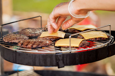 Close-up of person preparing food on barbecue grill