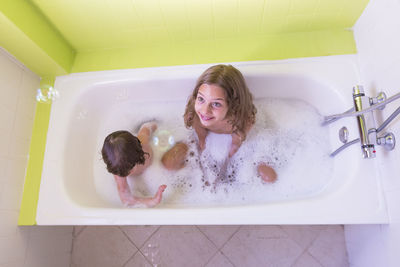 High angle view of happy siblings playing in bathtub