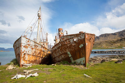 Abandoned boats on sea shore against sky
