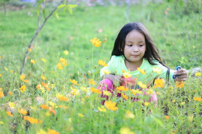 Girl with fidget spinner by flowers on field