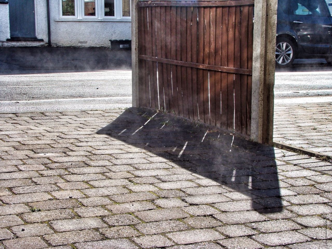 building exterior, built structure, architecture, street, sidewalk, cobblestone, outdoors, paving stone, day, city, footpath, transportation, bollard, sunlight, shadow, no people, safety, pavement, protection, road