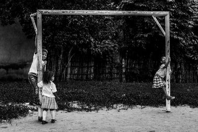 Friends playing with metallic built structure in playground