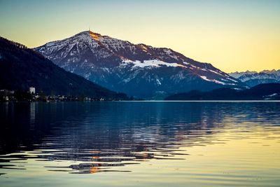 Scenic view of lake by snowcapped mountains against sky